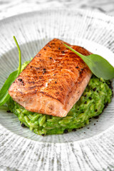 Grilled salmon fillet in avocado sauce in a festive plate on a marble background. Restaurant banquet menu.