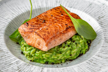 Grilled salmon fillet in avocado sauce in a festive plate on a marble background. Restaurant banquet menu.