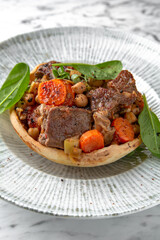 Roast beef or pork with potatoes and carrots in a festive plate on a marble background. Restaurant banquet menu.