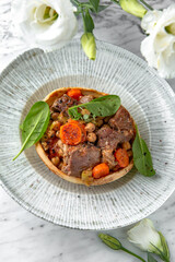 Roast beef or pork with potatoes and carrots in a festive plate on a marble background. Restaurant banquet menu.