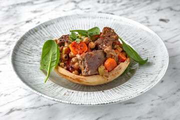 Roast beef or pork with potatoes and carrots in a festive plate on a marble background. Restaurant banquet menu.