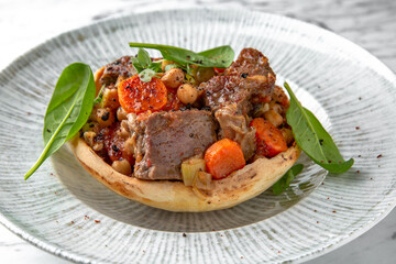 Roast beef or pork with potatoes and carrots in a festive plate on a marble background. Restaurant banquet menu.