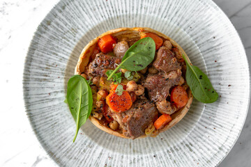 Roast beef or pork with potatoes and carrots in a festive plate on a marble background. Restaurant banquet menu.