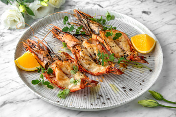 Grilled king prawns in a festive plate on a marble background. Restaurant banquet menu.