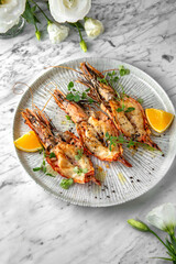 Grilled king prawns in a festive plate on a marble background. Restaurant banquet menu.