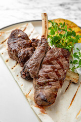 Grilled rack of lamb in a festive plate on a marble background. Restaurant banquet menu.