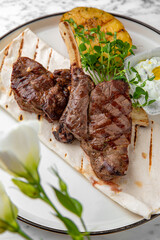 Grilled rack of lamb in a festive plate on a marble background. Restaurant banquet menu.