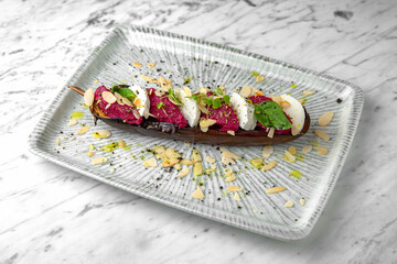 Baked eggplant with beetroot souffle with nuts and mozzarella in a festive plate on a marble background. Restaurant banquet menu.