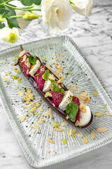 Baked eggplant with beetroot souffle with nuts and mozzarella in a festive plate on a marble background. Restaurant banquet menu.