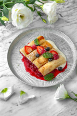 Pancakes or cheese cakes with condensed milk and berries in a festive plate on a marble background. Restaurant banquet menu.