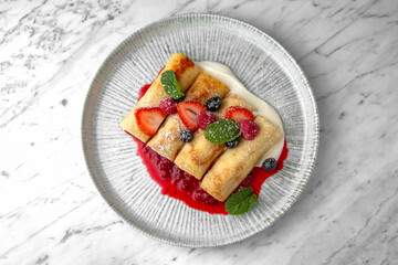 Pancakes or cheese cakes with condensed milk and berries in a festive plate on a marble background. Restaurant banquet menu.