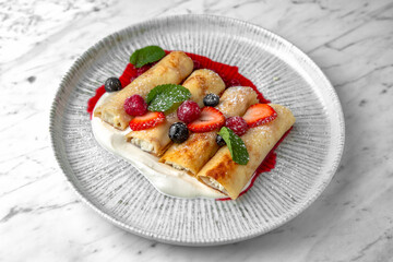 Pancakes or cheese cakes with condensed milk and berries in a festive plate on a marble background. Restaurant banquet menu.