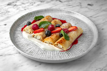 Pancakes or cheese cakes with condensed milk and berries in a festive plate on a marble background. Restaurant banquet menu.