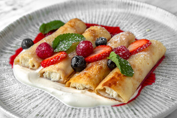 Pancakes or cheese cakes with condensed milk and berries in a festive plate on a marble background. Restaurant banquet menu.