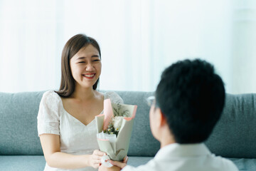 Man giving and surprise his wife a bouquet in their Valentine and wedding anniversary day. 