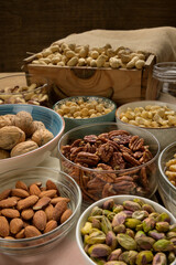 Different nuts and bowls closeup on a wooden table and brown background. Peanut, nut, cashew, almond, hazelnut, pistachio