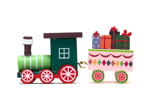 A toy steam locomotive carries a wagon with gifts. Feast of the Nativity of Christ. Isolated photo for design.