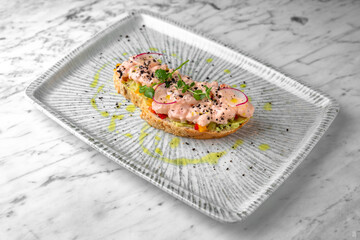 Bruschetta with tender cocktail shrimp, cucumber and radish in a festive plate on a marble background. Restaurant banquet menu.