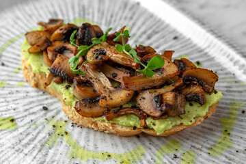 Bruschetta with guacamole and fried mushrooms in a festive plate on a marble background. Restaurant banquet menu.