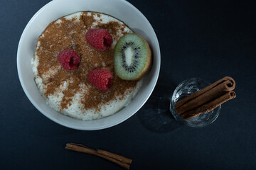 Traditional Finnish foods: a bowl of semolina porridge with cinnamon and sugar topping. Raspberries and a slice of kiwi fruit on the top.