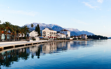 Fototapeta na wymiar Embankment of the town of Tivat surrounded by green palm trees against the backdrop of mountains