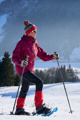 nice and active senior woman snowshoeing in  in the Allgau alps above lake Alpsee and Immenstadt, Bavaria, Germany