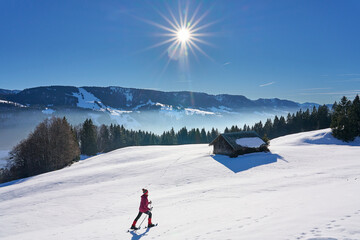 nice and active senior woman snowshoeing in  in the Allgau alps above lake Alpsee and Immenstadt, Bavaria, Germany