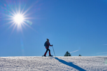 nice and active senior woman snowshoeing in  in the Allgau alps above lake Alpsee and Immenstadt, Bavaria, Germany