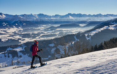 Fototapeta na wymiar nice and active senior woman snowshoeing in in the Allgau alps above Immenstadt, Bavaria, Germany 