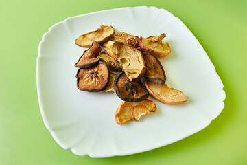 Apples cut into pieces and dried on a white plate. Dried fruits.