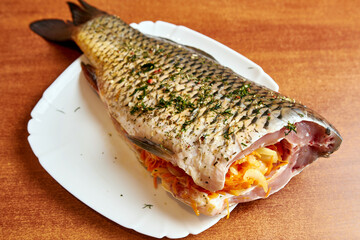 Cooking fish stuffed with carrots and onions.