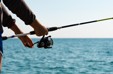 Close-up of man holding a fishing rod near the sea.