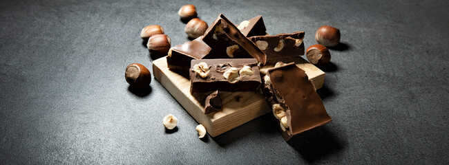 Gianduia nougat with chocolate and hazelnuts on dark gray background, space for text.. - 477869597