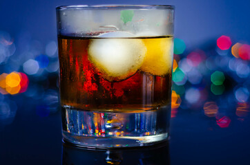 Drink Cuba Libre, rum with cola in an old fashoned glass with two ice balls