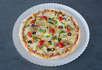 Delicious homemade Italian pizza with tomatoes and pea pods, corn olives, mushrooms and tomatoes. Top view close up