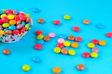 Colorful candies bowl on a blue background viewed from above. Top view