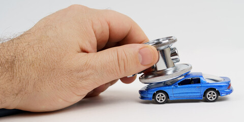 A stethoscope lies on the roof of a toy car. Car diagnostics, repair and maintenance concept