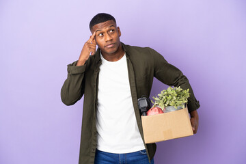 Latin man making a move while picking up a box full of things having doubts and thinking