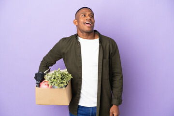 Latin man making a move while picking up a box full of things laughing