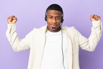 Telemarketer latin man working with a headset isolated on purple background doing strong gesture