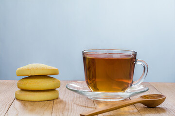 Tea in a transparent cup on a plate and cookies on a wooden table