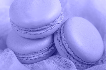 Delicious french dessert. Three gentle soft pastel Very Peri cakes  macaron or macaroon on airy fabric,
