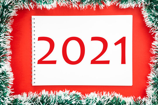 Summing up the results of 2021. Blank white sheet of notepad paper on red christmas background.
