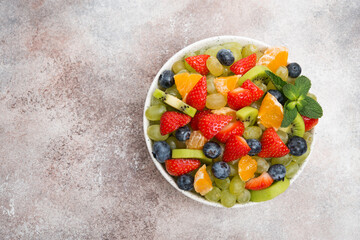 Fruit salad of blueberries, strawberries, grapes and kiwi in a plate, top view