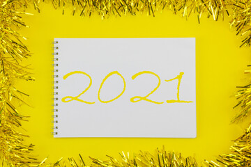 Summing up the results of 2021. A white sheet of paper on a yellow Christmas background with tinsel.