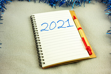 Summing up the results of 2021. A notebook with a pen on a blanket decorated with blue tinsel.