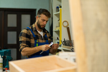 Bearded caucasian carpenter checking and measures drills