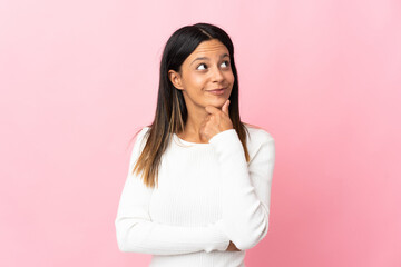 Fototapeta premium Caucasian girl isolated on pink background thinking an idea while looking up