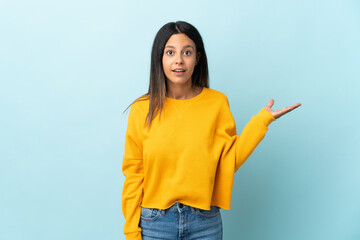 Caucasian girl isolated on blue background making doubts gesture