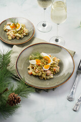 traditional east european dish for New Year's Eve - salad "Olivier" with potatoes, carrots, onion, peas, sausage eggs and mayonnaise on a green plate